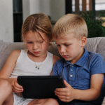 Enfants assis regardant écran noir brillant ensemble