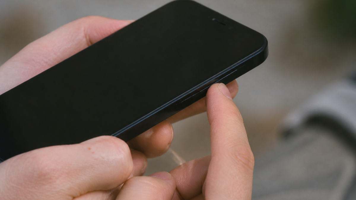 Doigt appuyant sur bouton lateral iPhone noir eteint