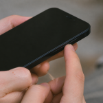 Doigt appuyant sur bouton lateral iPhone noir eteint