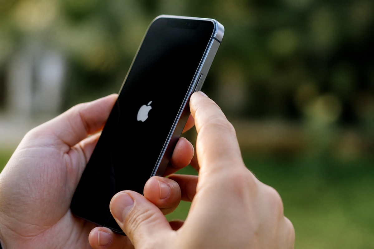 Doigt appuyant sur bouton lateral iPhone avec logo Apple affiche