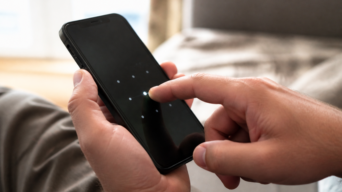 Doigt appuyant sur ecran iPhone noir affichant code verrouillage