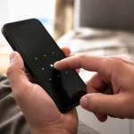 Doigt appuyant sur ecran iPhone noir affichant code verrouillage