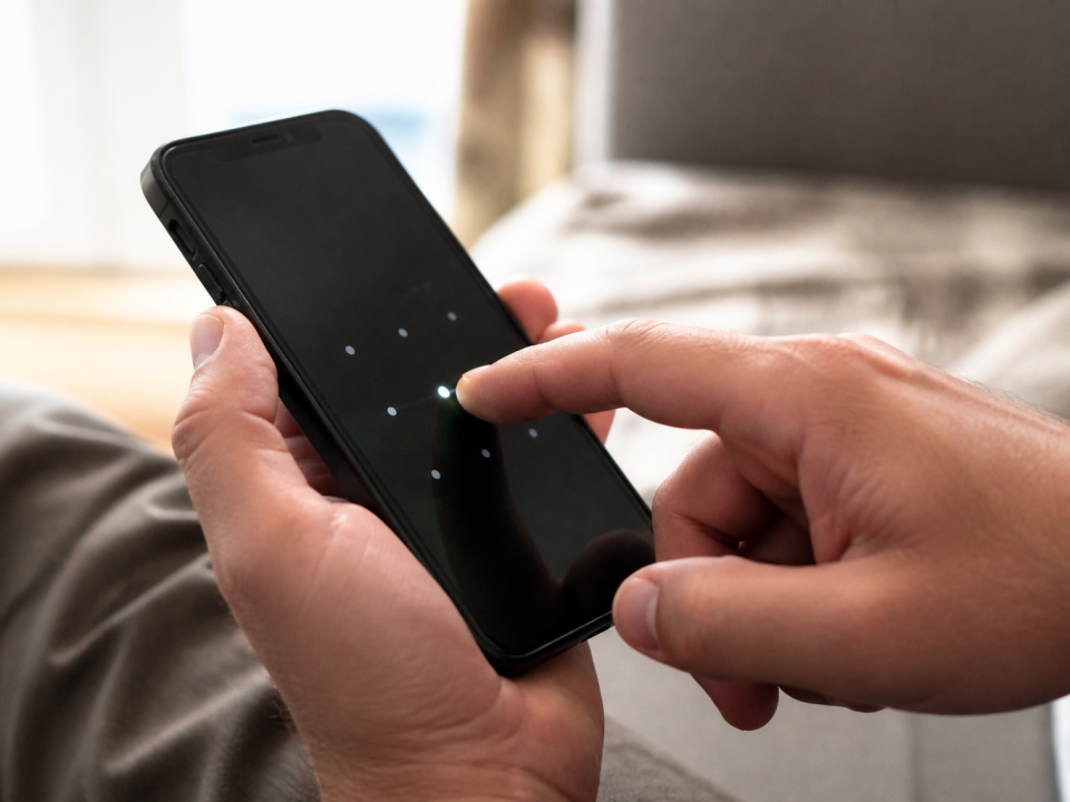 Doigt appuyant sur ecran iPhone noir affichant code verrouillage