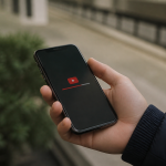 Main tenant iPhone affichant interface YouTube avec bouton telechargement visible