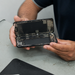 Technicien tenant iPhone 11 ouvert horizontalement, batterie visible