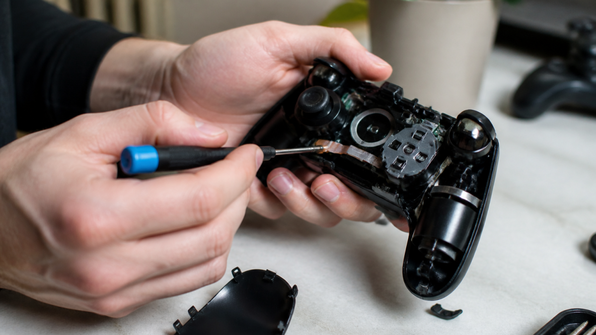 Mains tenant une manette PlayStation 5 noire demontee