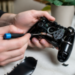 Mains tenant une manette PlayStation 5 noire demontee