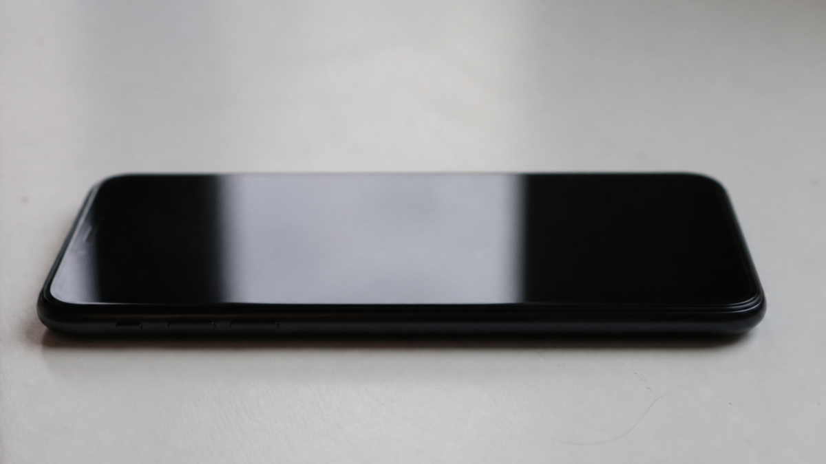 Smartphone Samsung noir posé horizontalement sur surface blanche