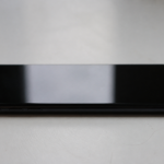 Smartphone Samsung noir posé horizontalement sur surface blanche