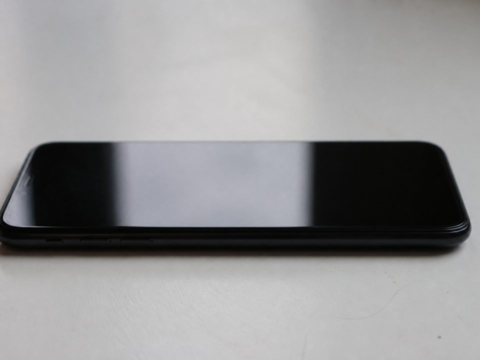 Smartphone Samsung noir posé horizontalement sur surface blanche