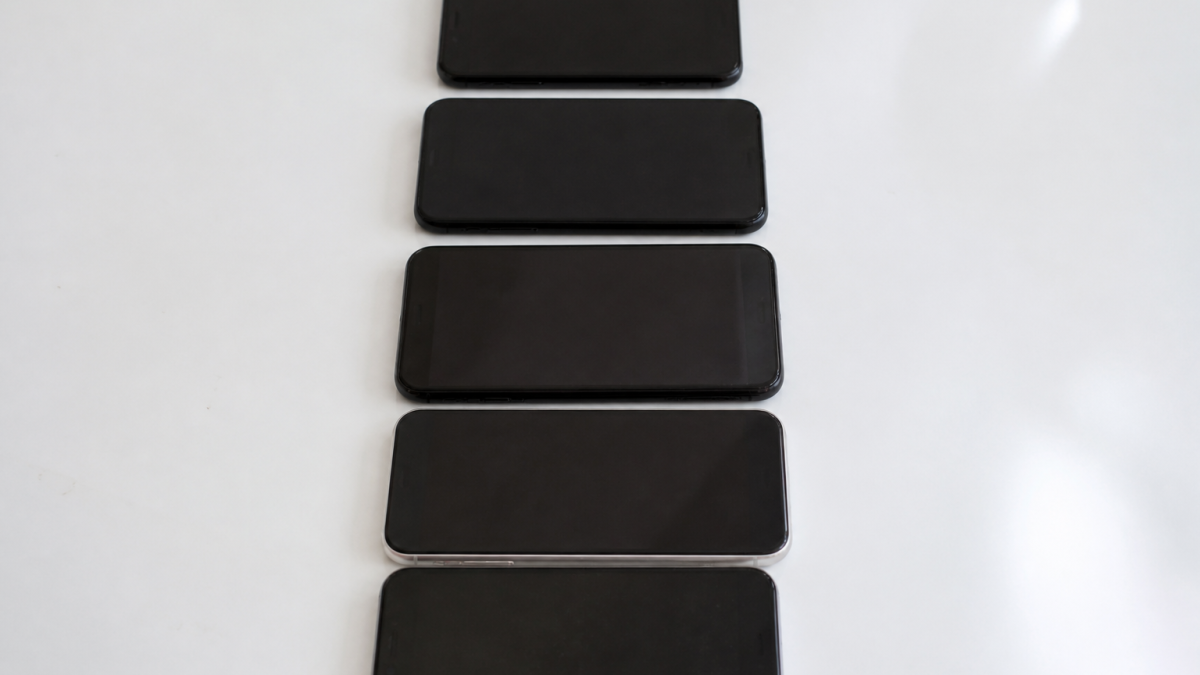 Plusieurs telephones mobiles aligns verticalement sur surface blanche