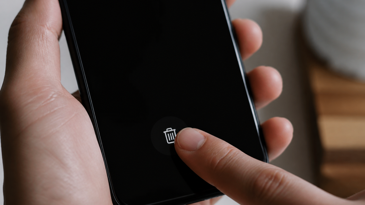 Doigt appuyant sur icone corbeille smartphone ecran noir