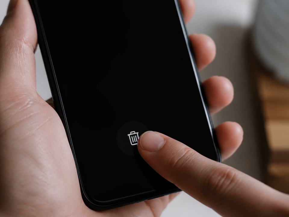 Doigt appuyant sur icone corbeille smartphone ecran noir