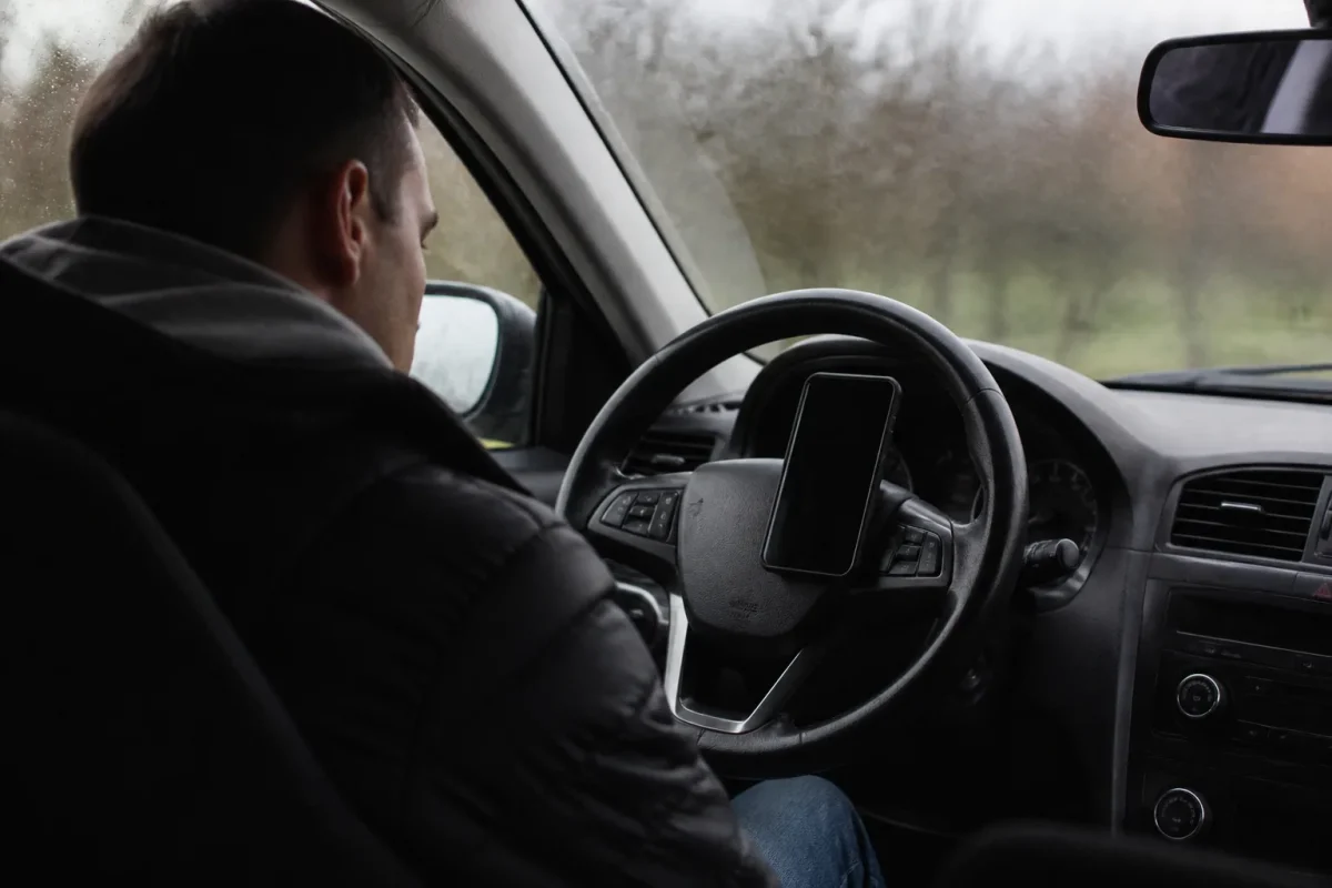 Conducteur regardant un telephone pose sur le volant