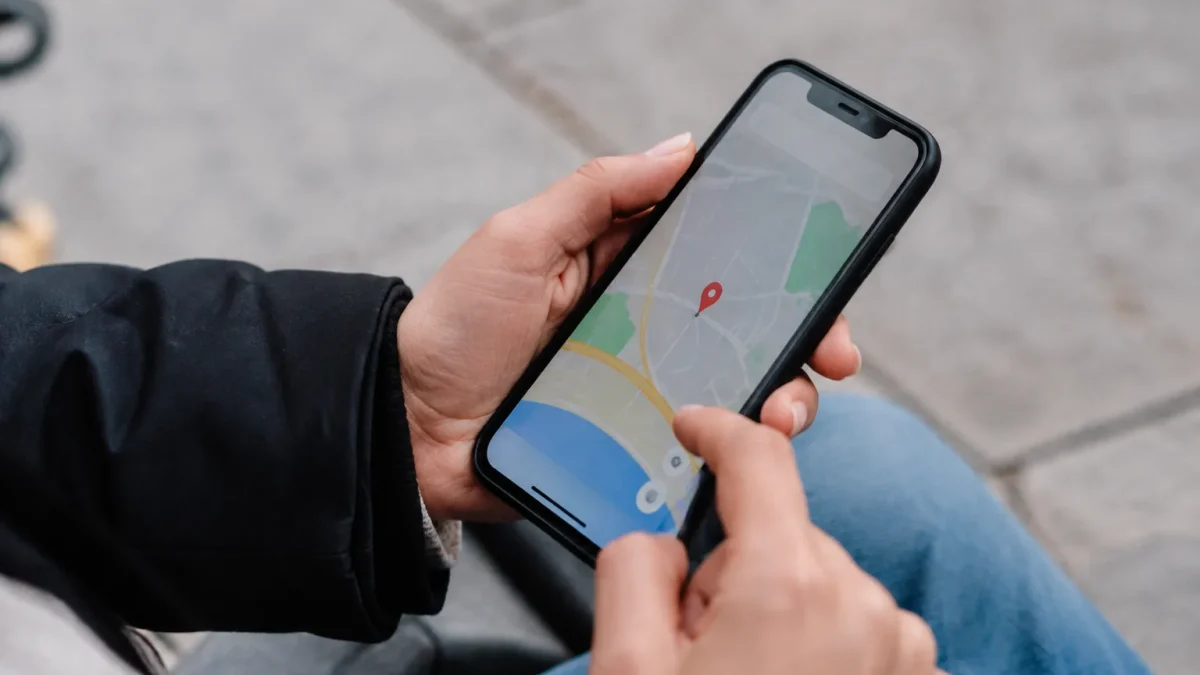 Main tenant smartphone affichant carte avec repere rouge