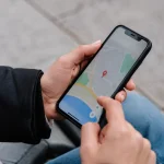 Main tenant smartphone affichant carte avec repere rouge