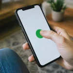 Main tenant smartphone incline, pouce touchant bouton vert