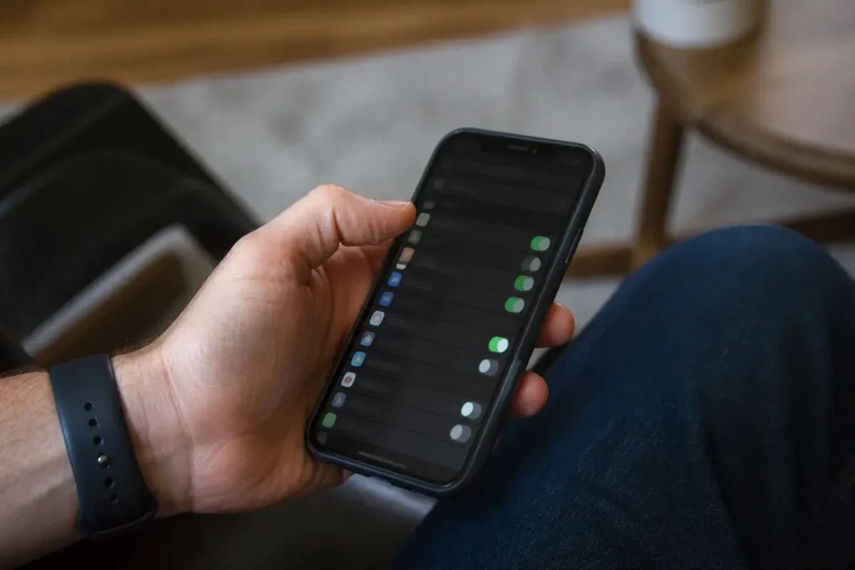 Main tenant un smartphone affichant une liste de reglages