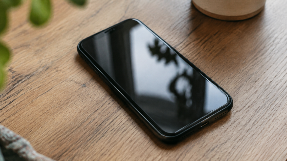 Main tenant smartphone pose sur table en bois