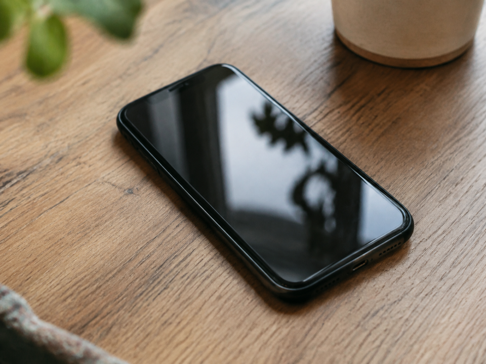 Main tenant smartphone pose sur table en bois