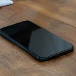 Smartphone noir pose a plat sur table en bois