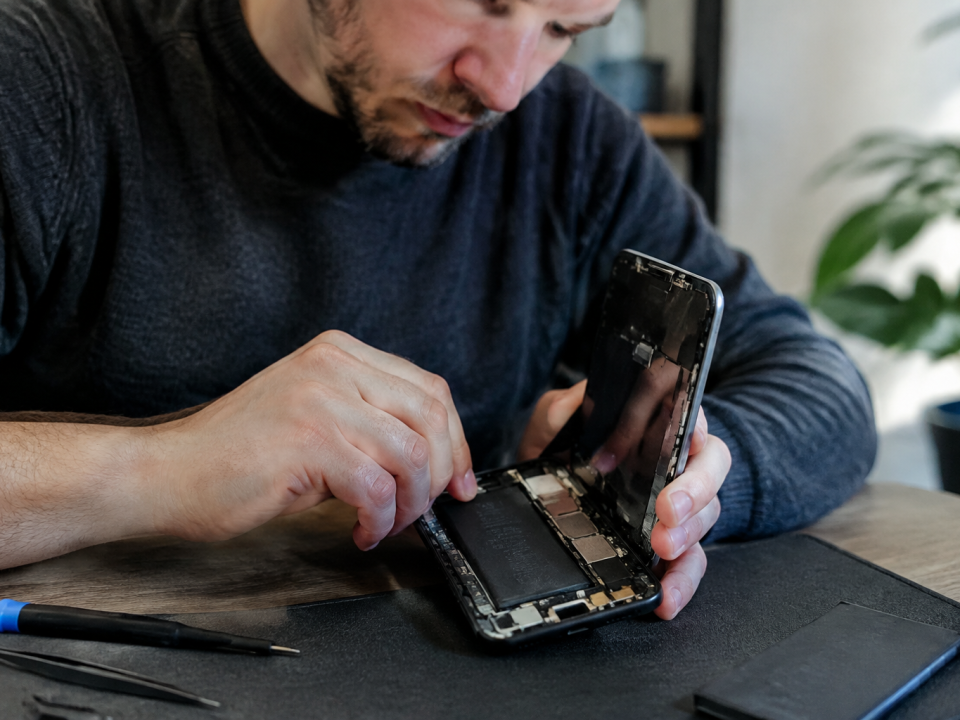Technicien tient smartphone ouvert pour remplacer accu