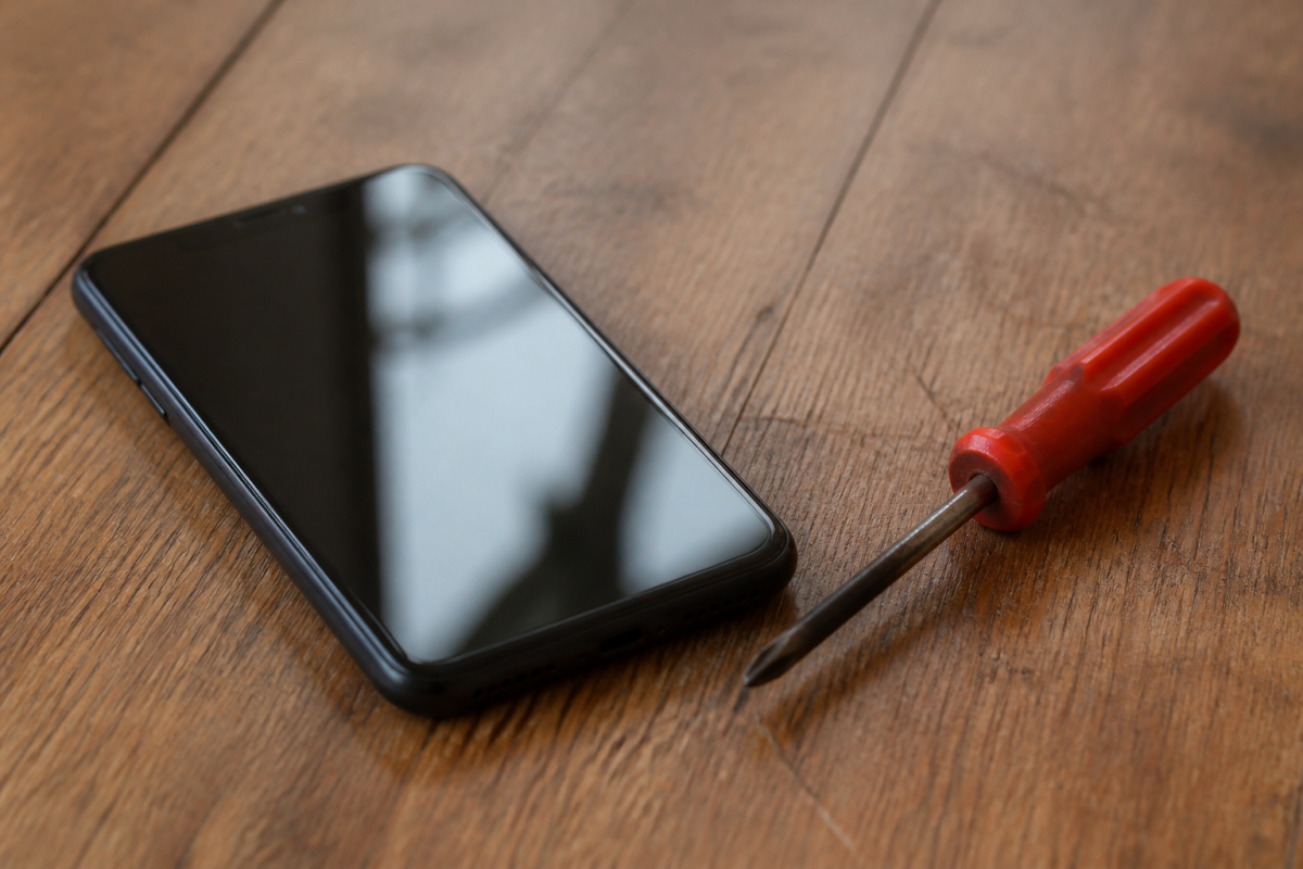 Vieux smartphone pose sur table avec tournevis